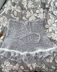 a grey crocheted skirt on a bed