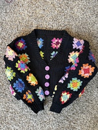 a black sweater with colorful flowers on it