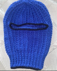 a blue knitted ninja hat on a bed