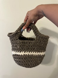 a person holding a small crocheted bag