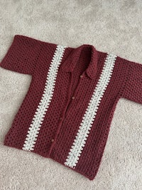 a burgundy and white crocheted cardigan on the carpet