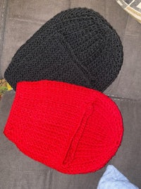 two red and black knitted hats on a couch