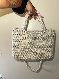 a person holding a crocheted tote bag