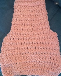 a pink crocheted blanket sitting on a couch