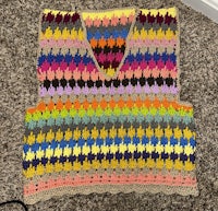 a colorful crocheted vest sitting on a carpet