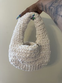 a person holding a crocheted bag with tattoos on it