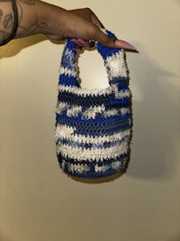 a person holding a blue and white crocheted bag